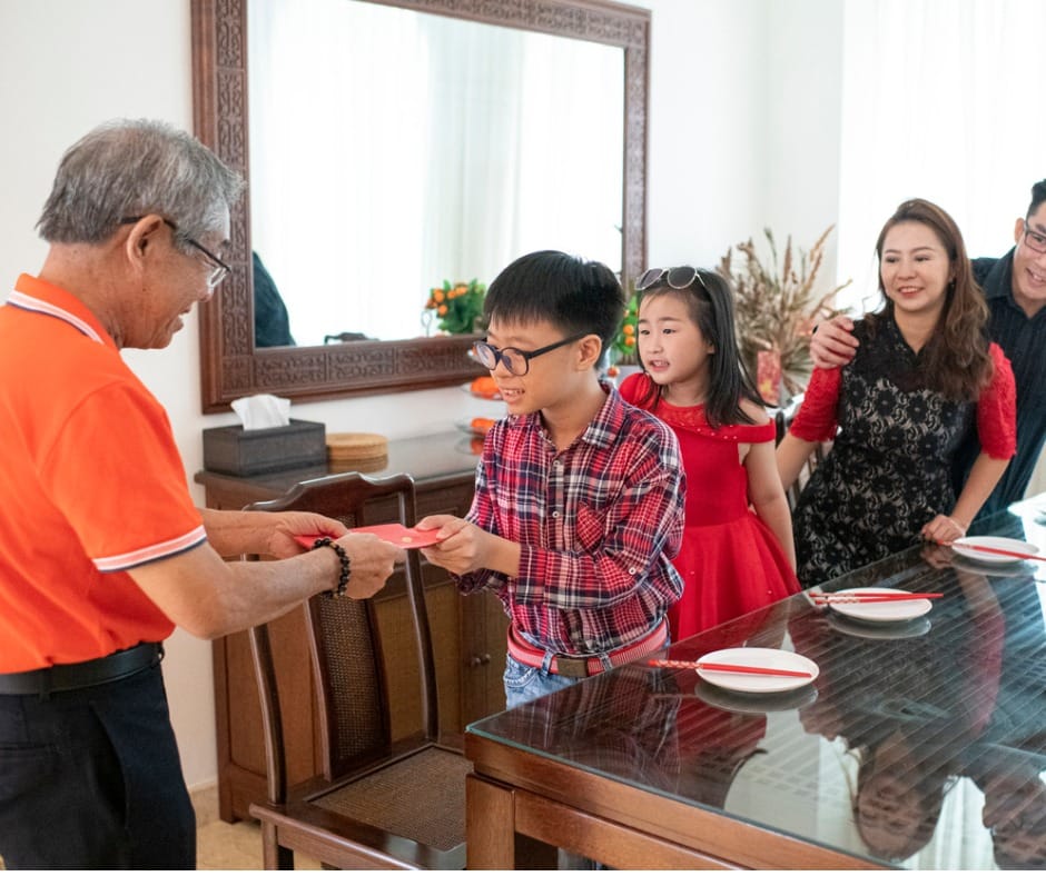 grandfather giving red packet angpao to his grandson during chinese new year